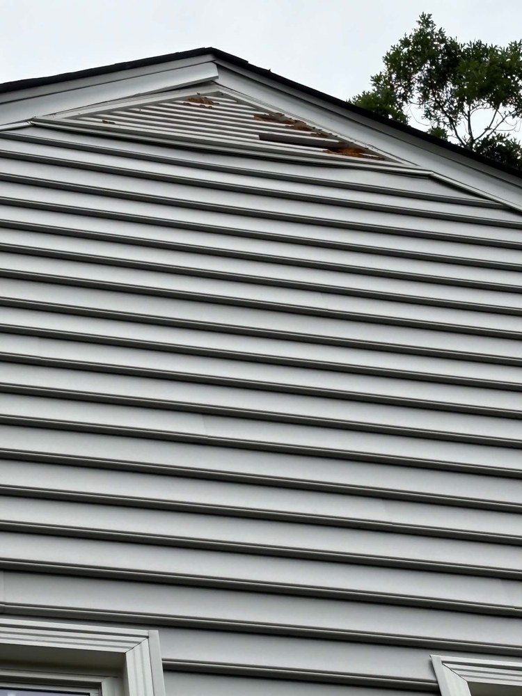 Wood rot and storm damage to siding and trim before repair by Magothy Roofing and Exteriors