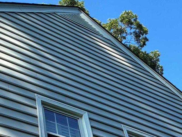Completed vinyl siding gable with new windows after repair